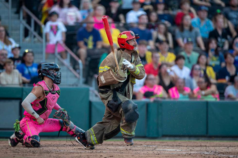 Firefighters’ Joe Lytle hits the ball while wearing bunker gear during the game against ...