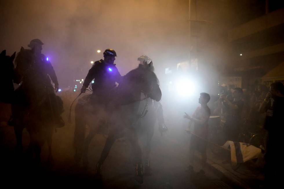 Israeli mounted police officers disperse demonstrators blocking a road during a protest against ...