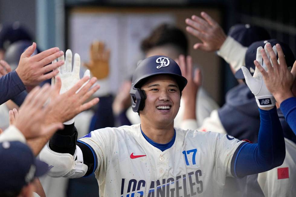 Los Angeles Dodgers' Shohei Ohtani, left, is congratulated by teammates in the dugout after hit ...