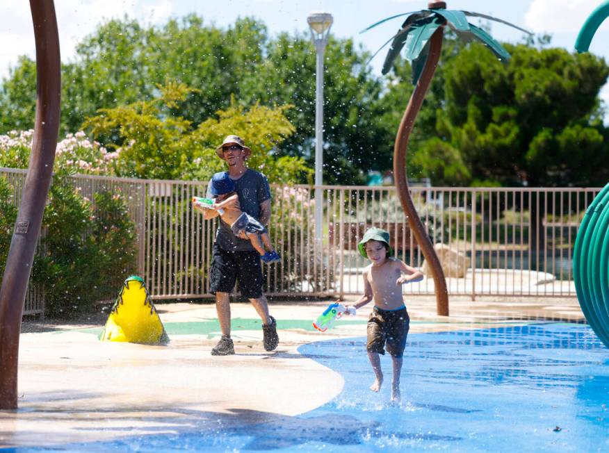 Seth Williams of Las Vegas plays in the splash pad with his sons Ambrose, 2, and Garrus, 4, at ...