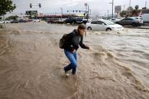 A pedestrian walks down a flooded sidewalk on Eastern Avenue south of Sahara Avenue Friday, Sep ...