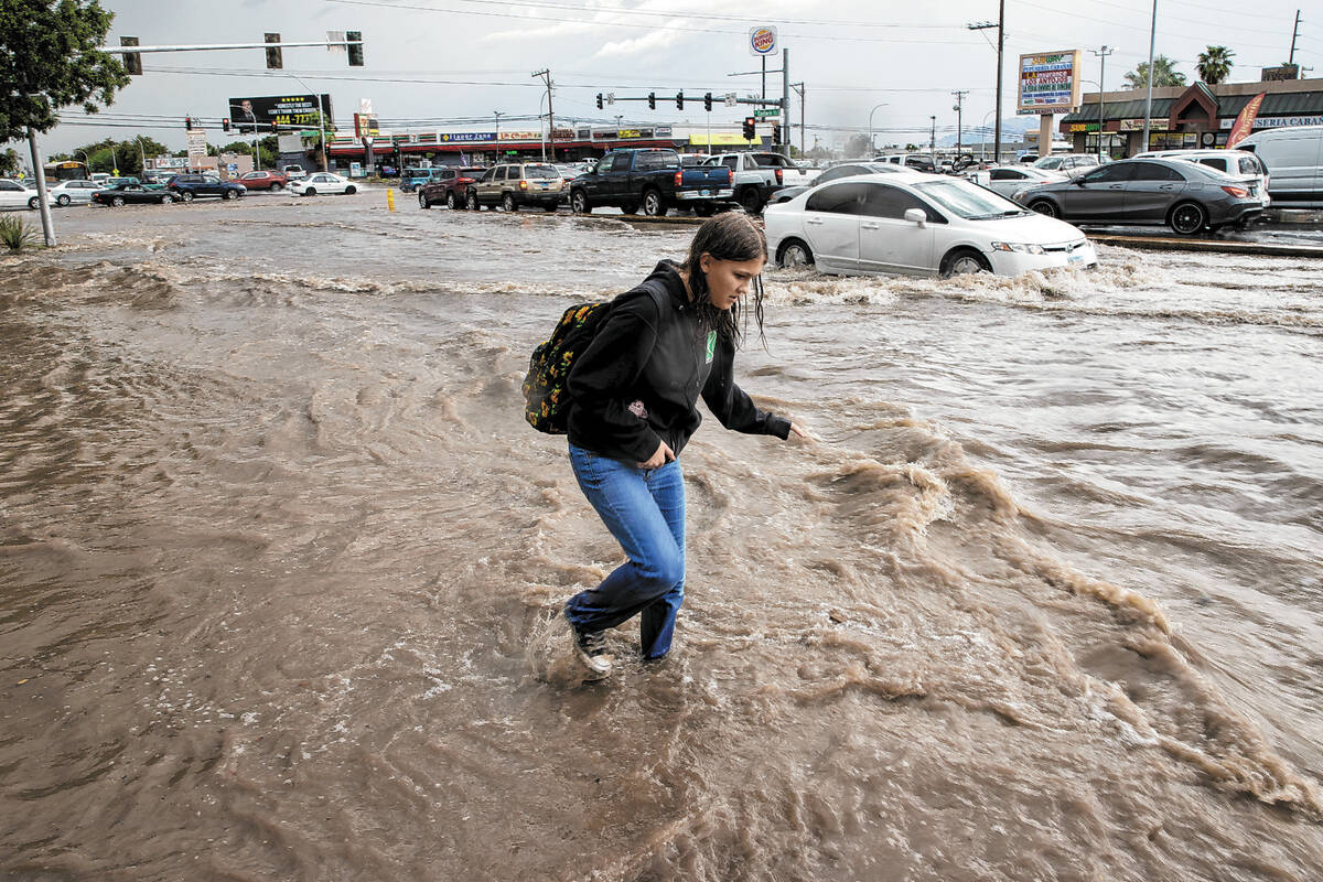 A pedestrian walks down a flooded sidewalk on South Eastern Avenue Friday, Sept. 1, 2023, in La ...