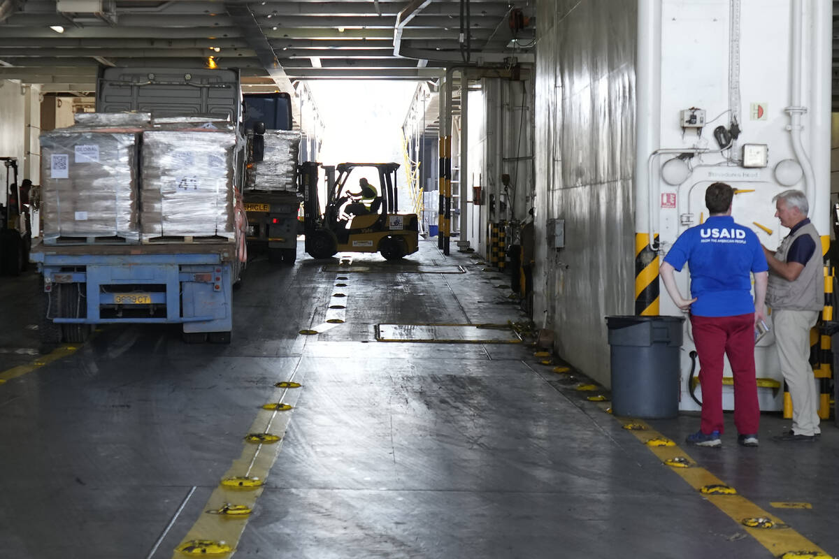 Members staff of U.S Aid, stand at right as a worker unloads Gaza aid from a truck inside a U.S ...