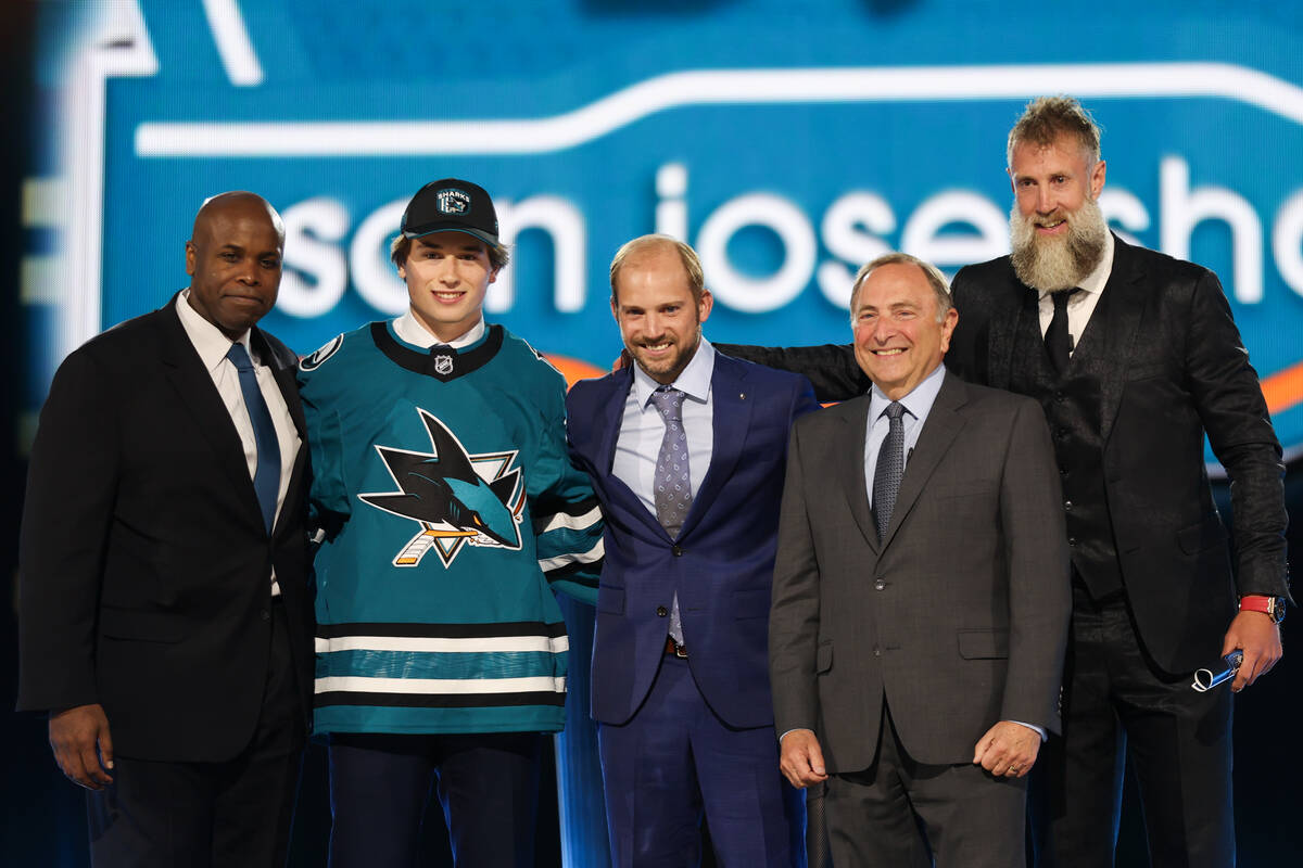Center Macklin Celebrini, flanked by San Jose Sharks and NHL leadership poses after the Sharks ...