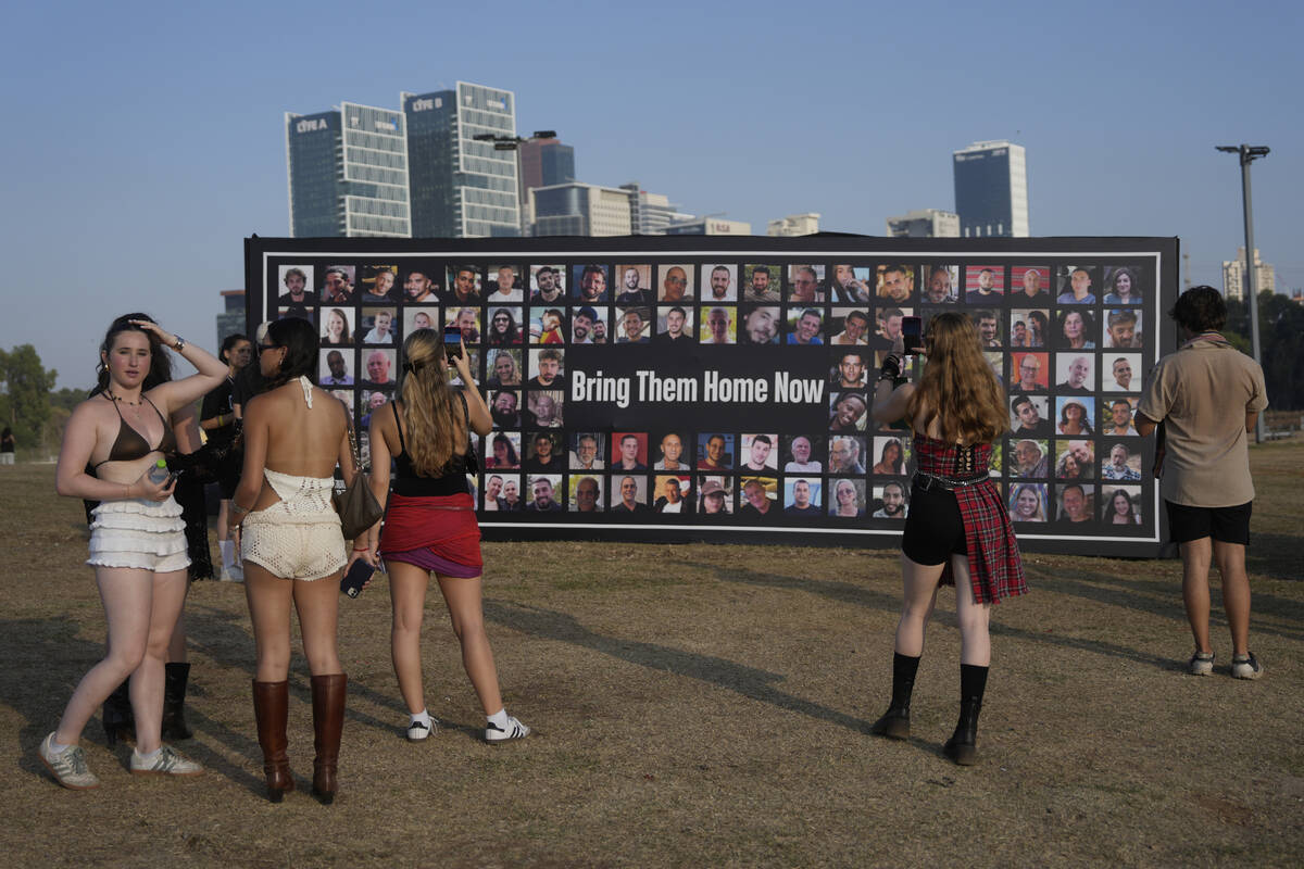 People pause at a picture display of hostages held in the Gaza Strip at the Nova Healing Concer ...