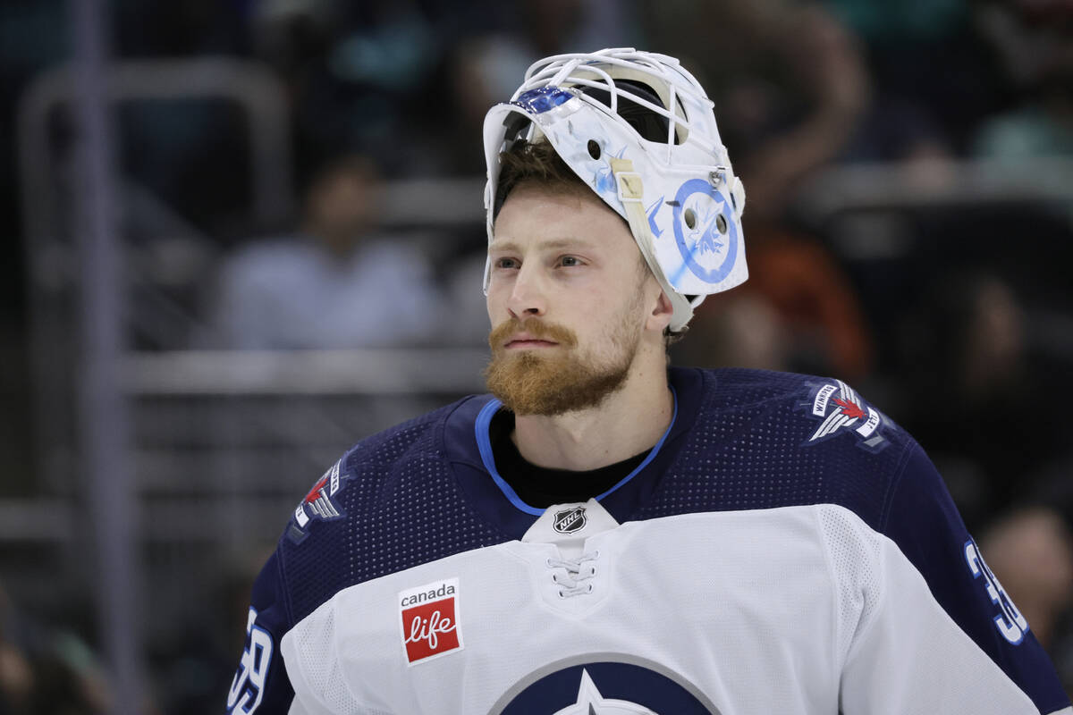 Winnipeg Jets goaltender Laurent Brossoit (39) on the ice with his helmet tipped back waiting f ...