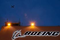 An airplane flies over a sign on Boeing's newly expanded 737 delivery center, Oct. 19, 2015, at ...