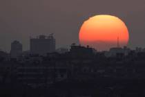 The sun sets behind the buildings in the Gaza Strip as seen from southern Israel, Saturday, Jun ...