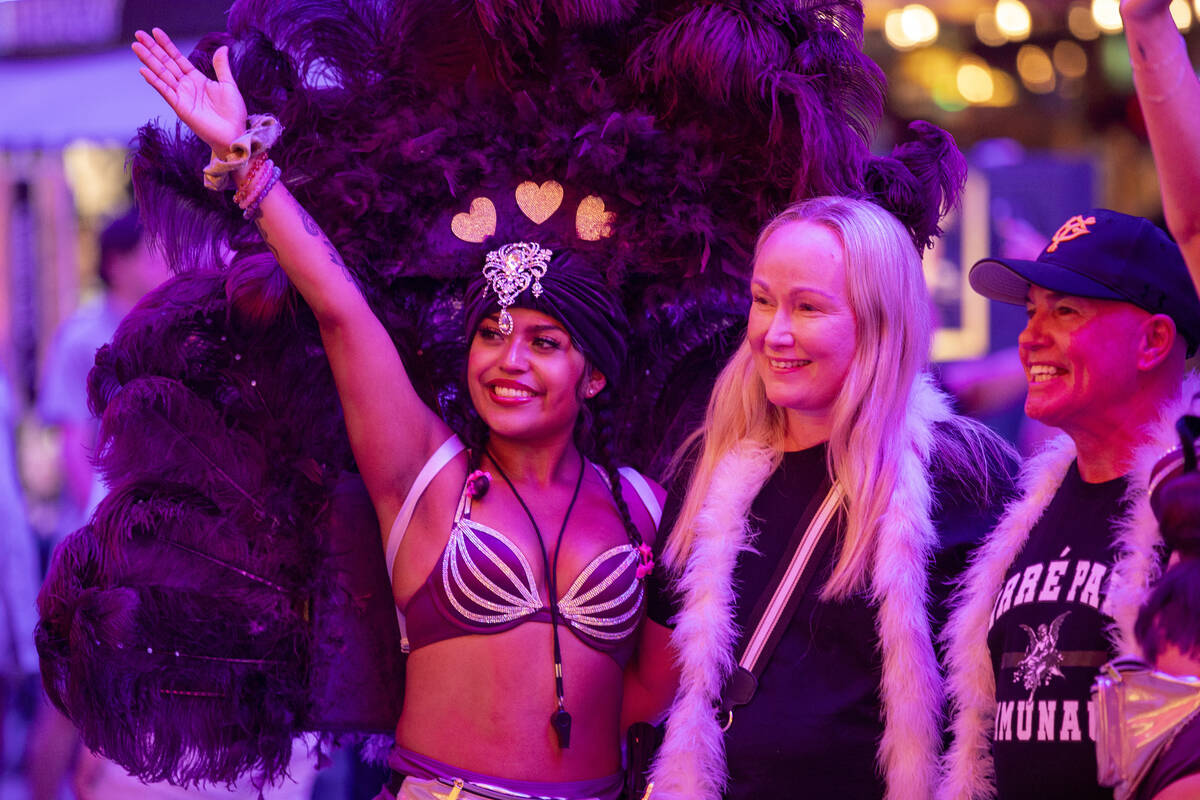 Tourists take photographs with a couple of showgirls at the Fremont Street Experience Monday, J ...