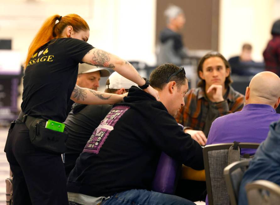 A massage therapist gives a poker player a massage during the first day of the World Series of ...