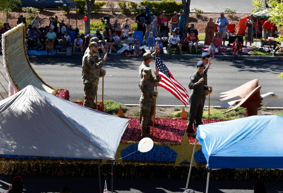 Members of the military wave to the crowd from the All-Star Salute to the Military float during ...