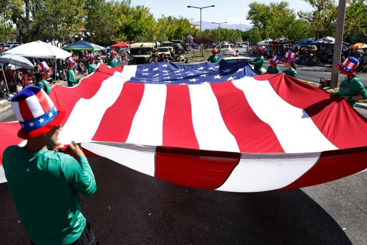 Nick Meis, left, Palo Verde cross country men's head coach, and students wave a giant American ...