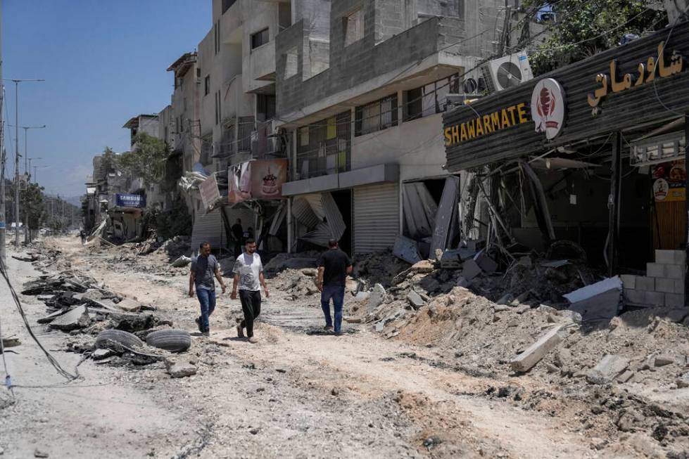 Palestinians walk along a damaged road following an Israeli operation in Nur Shams refugee camp ...