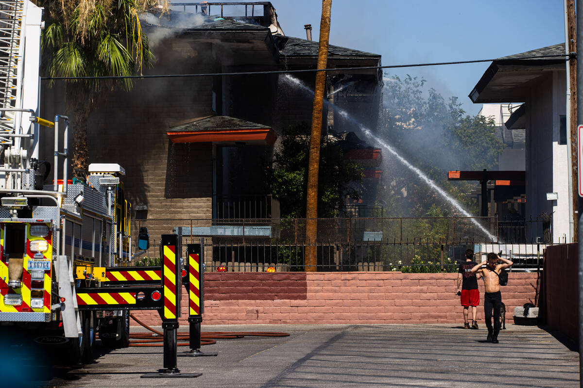 Clark County firefighters work to contain an apartment fire as people look on along Dumont Boul ...
