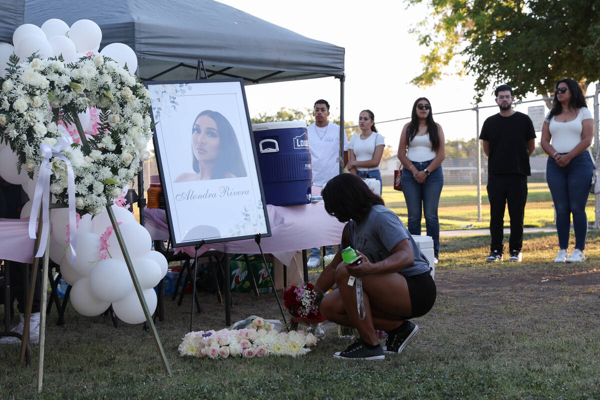 A loved one of Alondra Rivera places flowers during a vigil at Winterwood Park on Wednesday, Ju ...