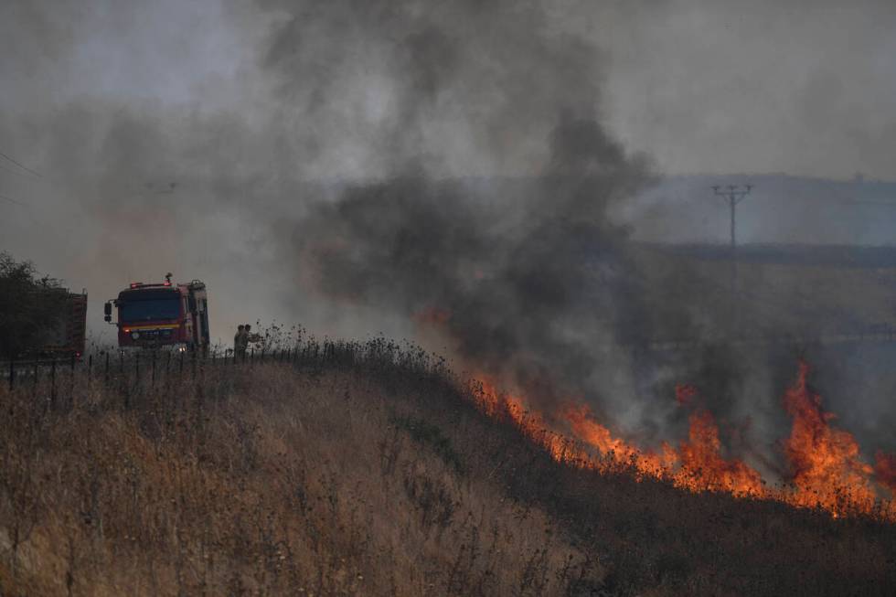 Firefighters work to extinguish a fire following an attack from Lebanese Hezbollah group, in an ...