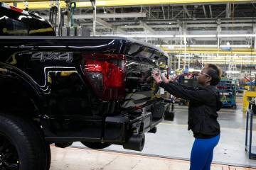 FILE - Assembly line worker Lashunta Harris applies the Ford logo on a 2024 Ford F-150 truck be ...