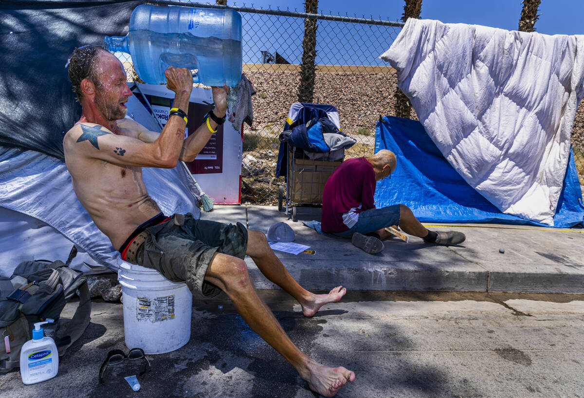 Homeless man Milton John Scott III pours a jug of water on his head to escape the heat and wash ...