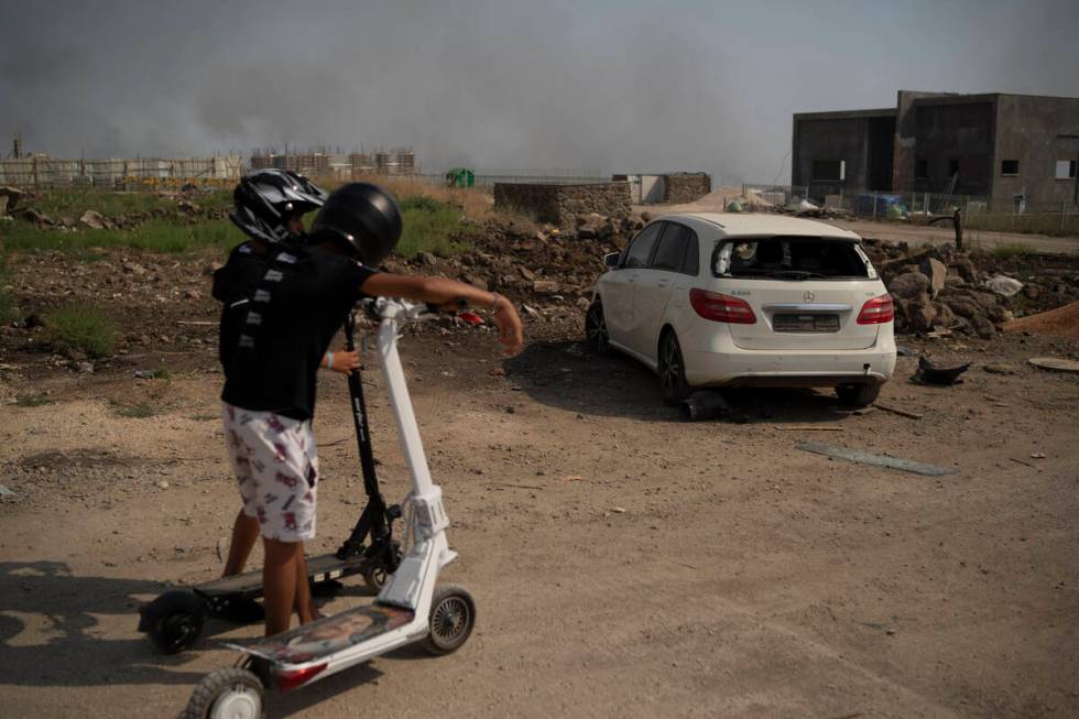 Boys look at a damaged car after shelling fired from Lebanon in Katsrin, a city near the border ...