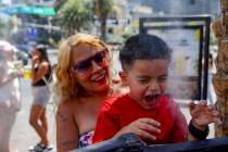 Kathy Martinez, of Las Vegas, holds her godson Josiah Ornelas, 6, over misters to cool down out ...