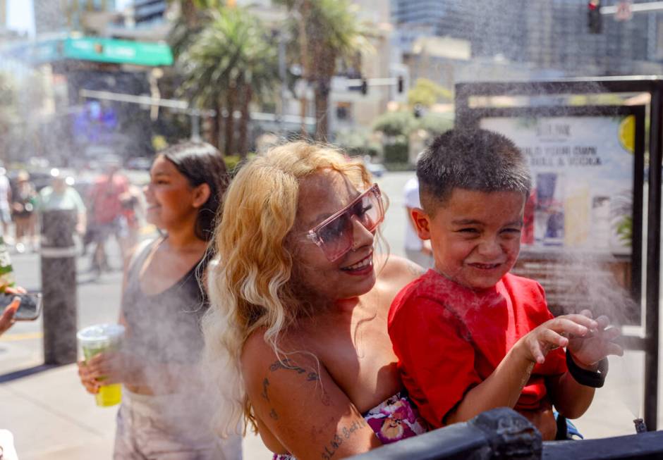 Kathy Martinez, of Las Vegas, holds her godson Josiah Ornelas, 6, over misters to cool down out ...