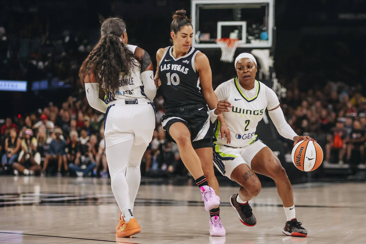 Aces guard Kelsey Plum (10) weaves herself through Dallas Wings guard Arike Ogunbowale (24) and ...