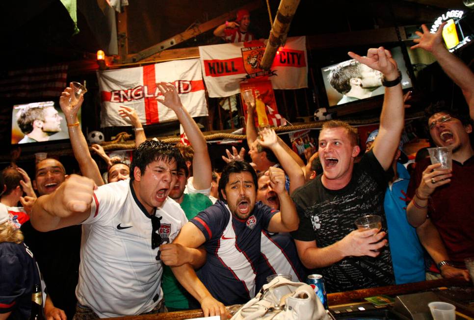 USA soccer fans including Luis Castillo, left, and Ricardo Fino, center, cheer after team USA s ...