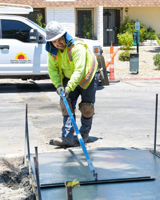 Alex Horta from Sunrise Paving smooths fresh concrete as they replace a sidewalk on the East si ...