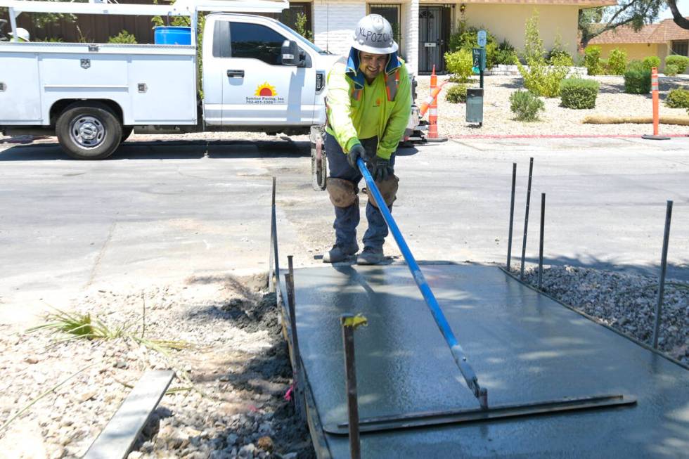 Alex Horta from Sunrise Paving smooths fresh concrete as they replace a sidewalk on the East si ...