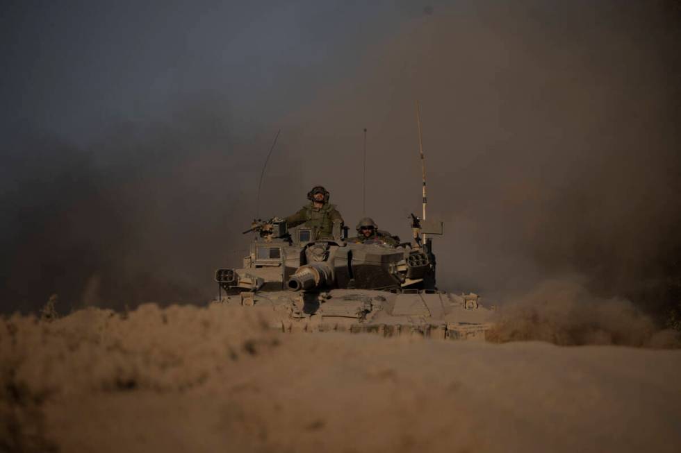 Israeli soldiers move on the top of a tank near the Israeli-Gaza border, as seen from southern ...