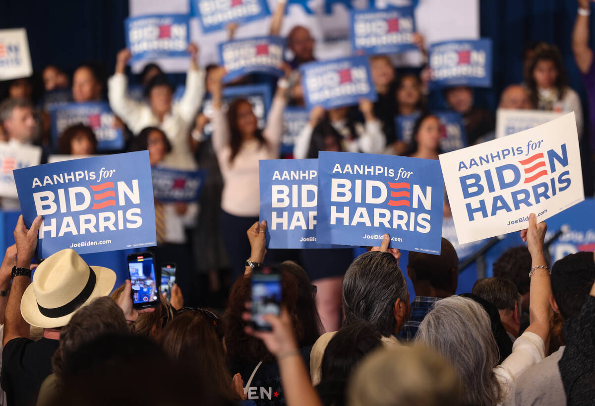Supporters wave signs at a campaign event for Vice President Kamala Harris at Resorts World Las ...