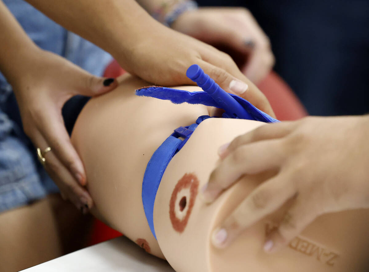 Students practice to stop the flow of blood by using tourniquet, a device for stopping the flow ...
