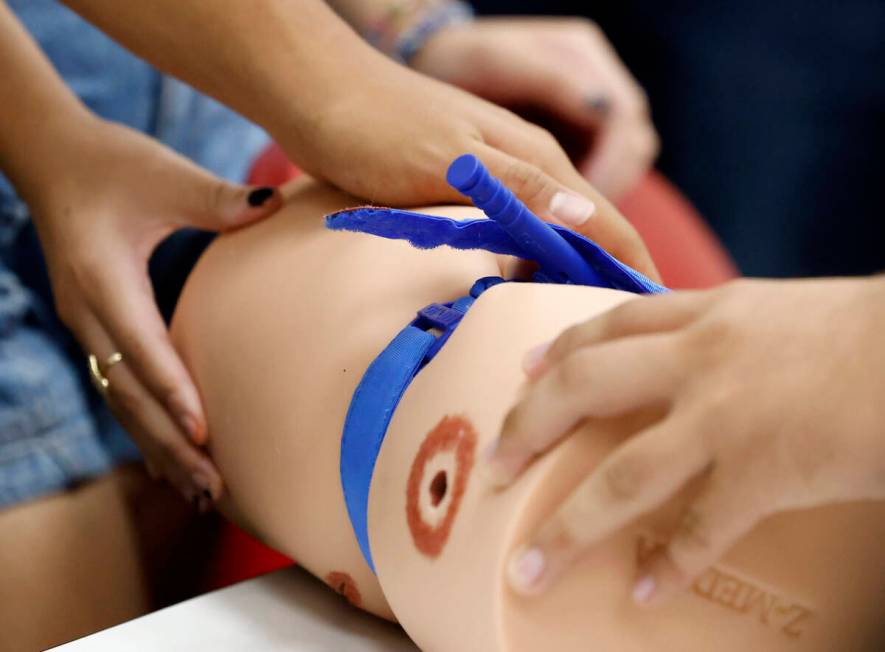 Students practice to stop the flow of blood by using tourniquet, a device for stopping the flow ...