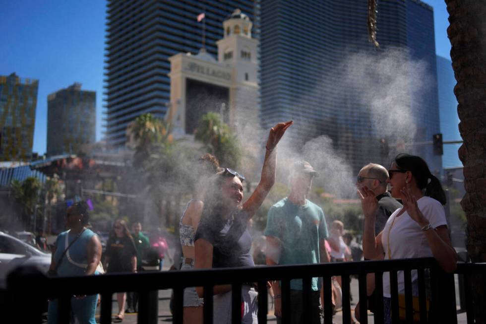 People cool off in misters along the Las Vegas Strip, Sunday, July 7, 2024, in Las Vegas. A hea ...