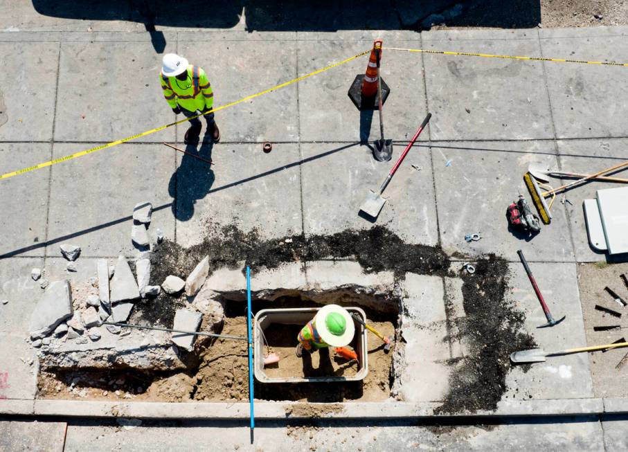 Workers install electric box on the sidewalk at the intersection of Maryland Parkway and Charle ...