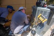 Dijon Sims, left, and Steve Kendrick, right, install a new HVAC unit at Kit Herron’s home Fri ...