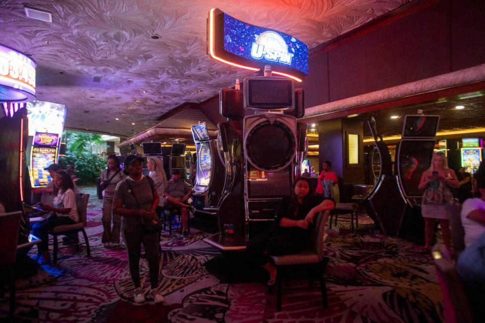 Tourists sit at old slot machines, waiting for a usable one to open up, in The Mirage, Wednesda ...