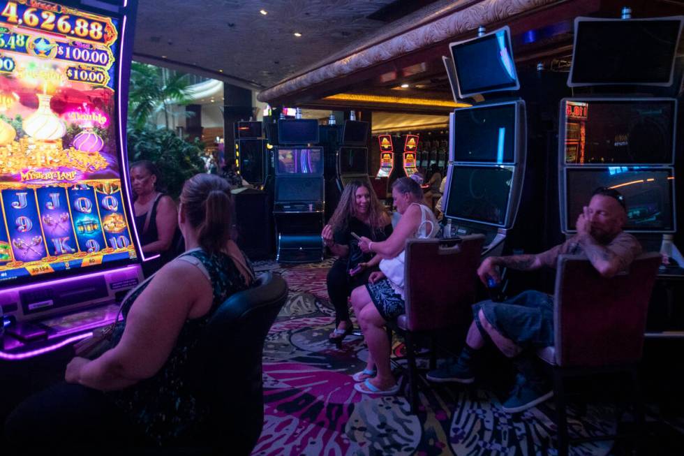 Tourists sit at old slot machines, waiting for a usable one to open up, in The Mirage, Wednesda ...