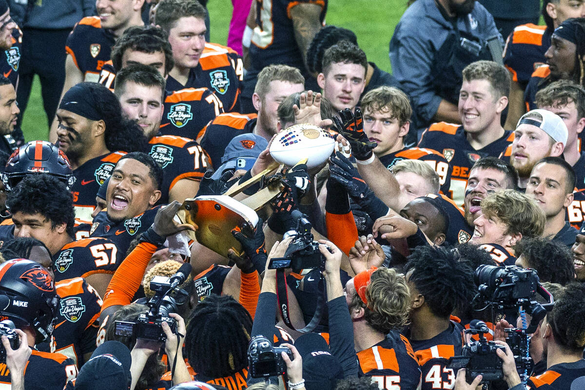 Oregon State Beavers players touch and pass along the Rossi Ralenkotter trophy after defeating ...