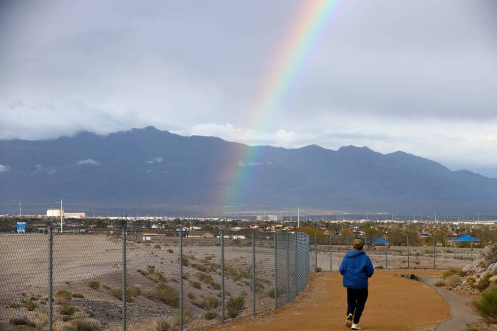 A runner makes way around Lone Mountain under a rainbow as rain showers the Las Vegas Valley on ...