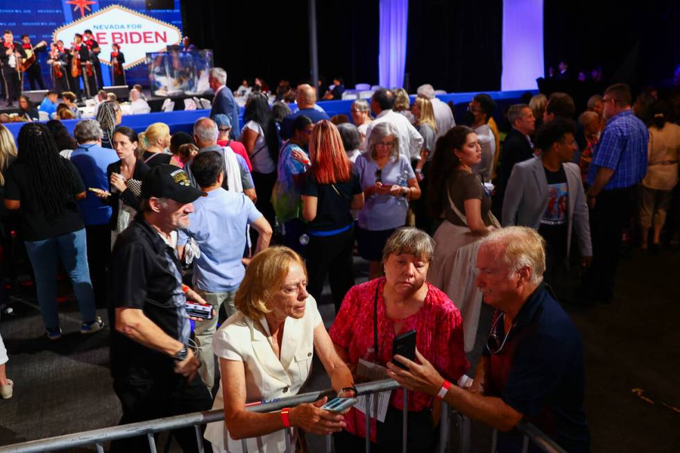 Attendees of a campaign event for President Joe Biden look for news of the President’s w ...