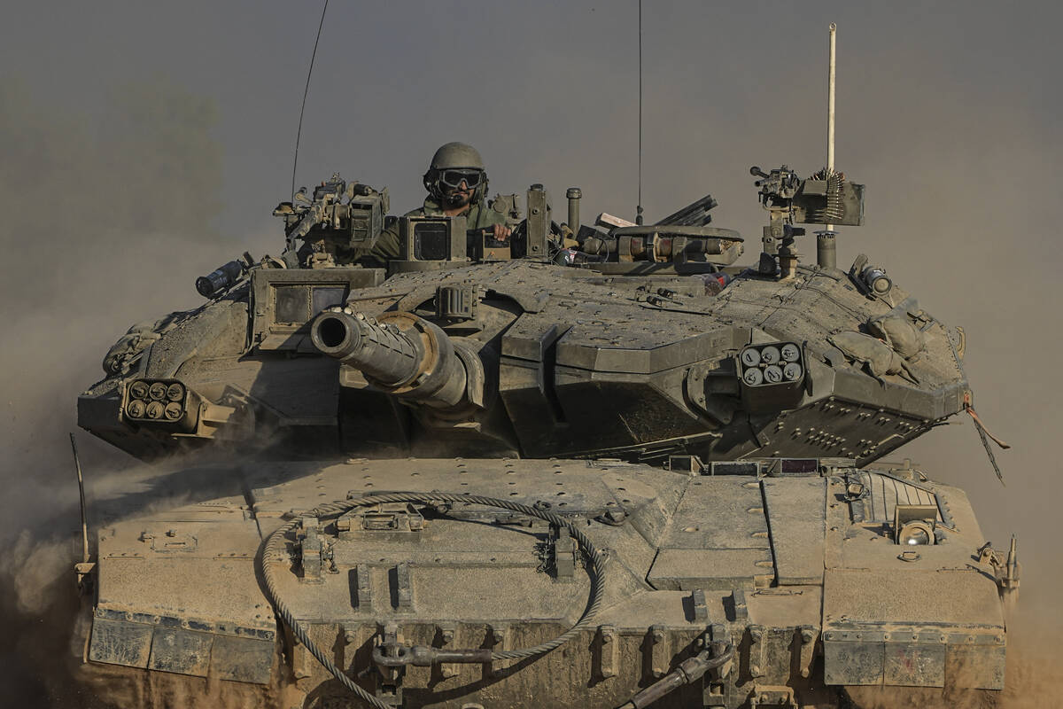An Israeli soldier moves on the top of a tank near the Israeli-Gaza border, as seen from southe ...