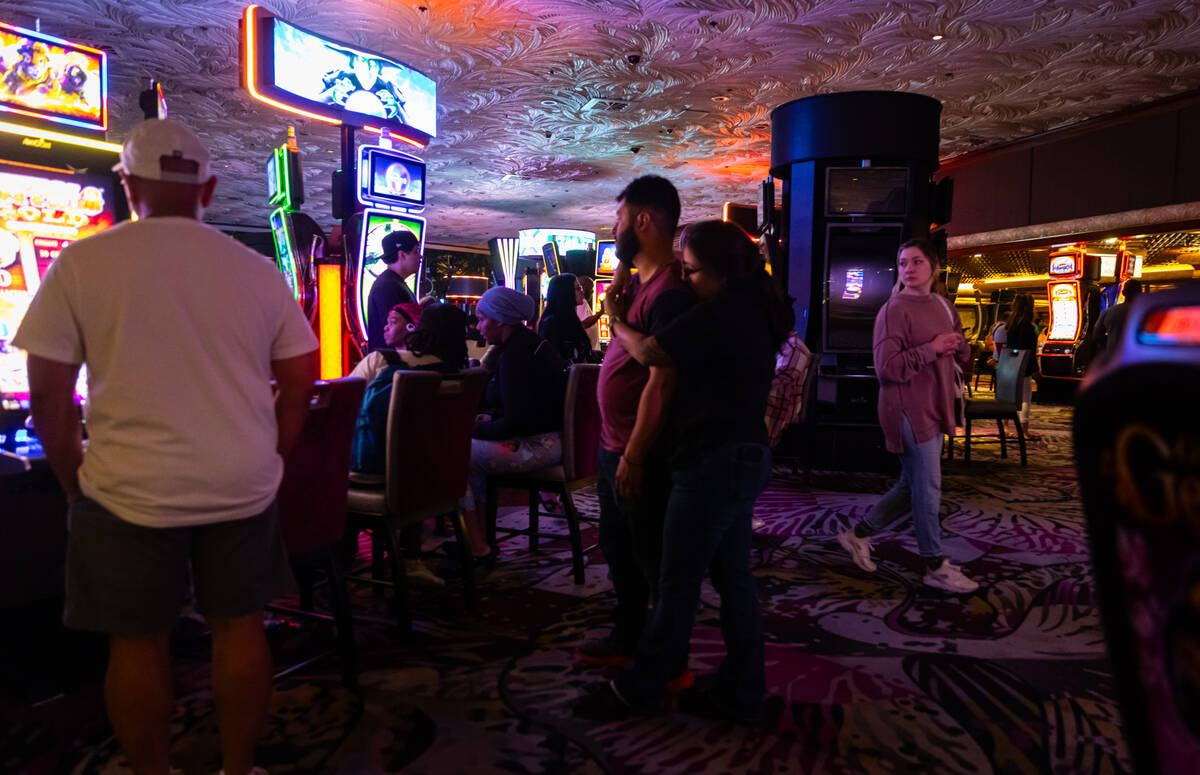 People stand by as others play the remaining slot machines during the final night of operations ...