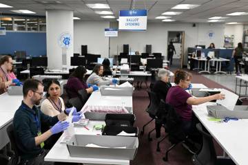 County employees open ballots in the ballot opening area of the mail ballot processing room at ...