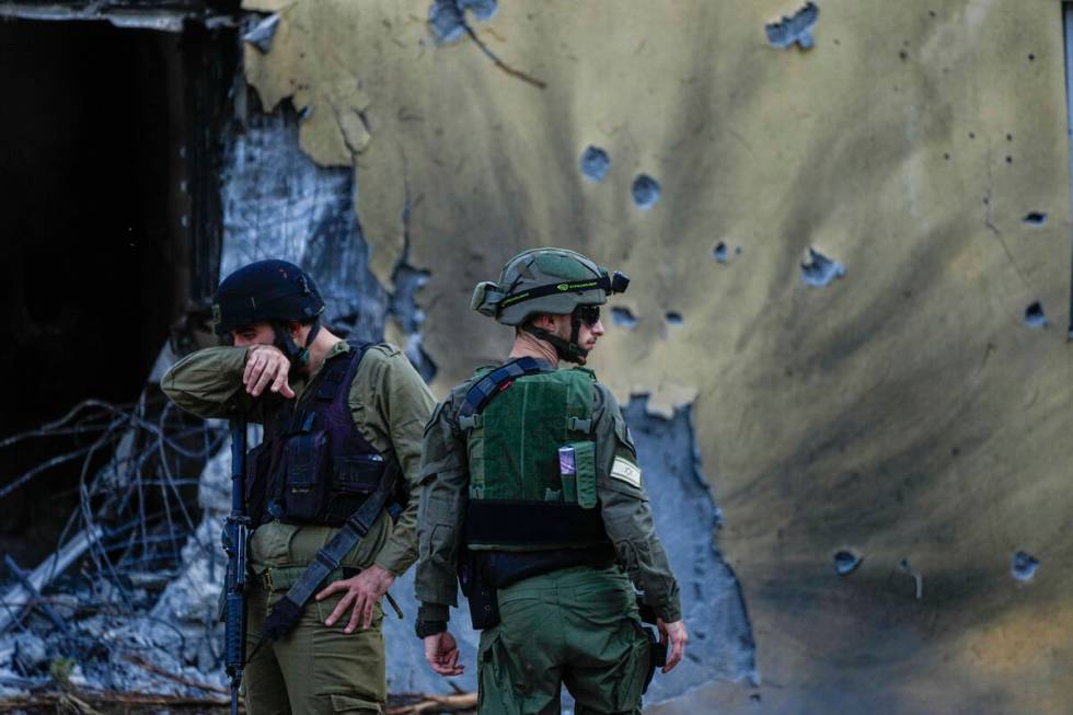 FILE - Israeli soldiers walk past houses destroyed by Hamas militants in Kibbutz Be'eri, Israel ...