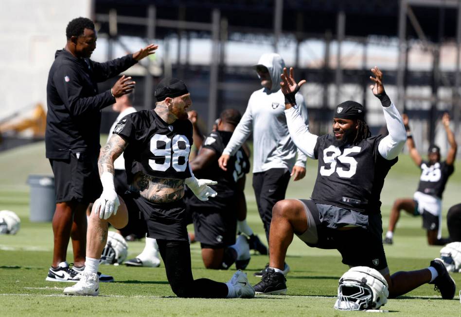 Raiders defensive end Maxx Crosby (98) and defensive tackle John Jenkins (95) chat with defensi ...