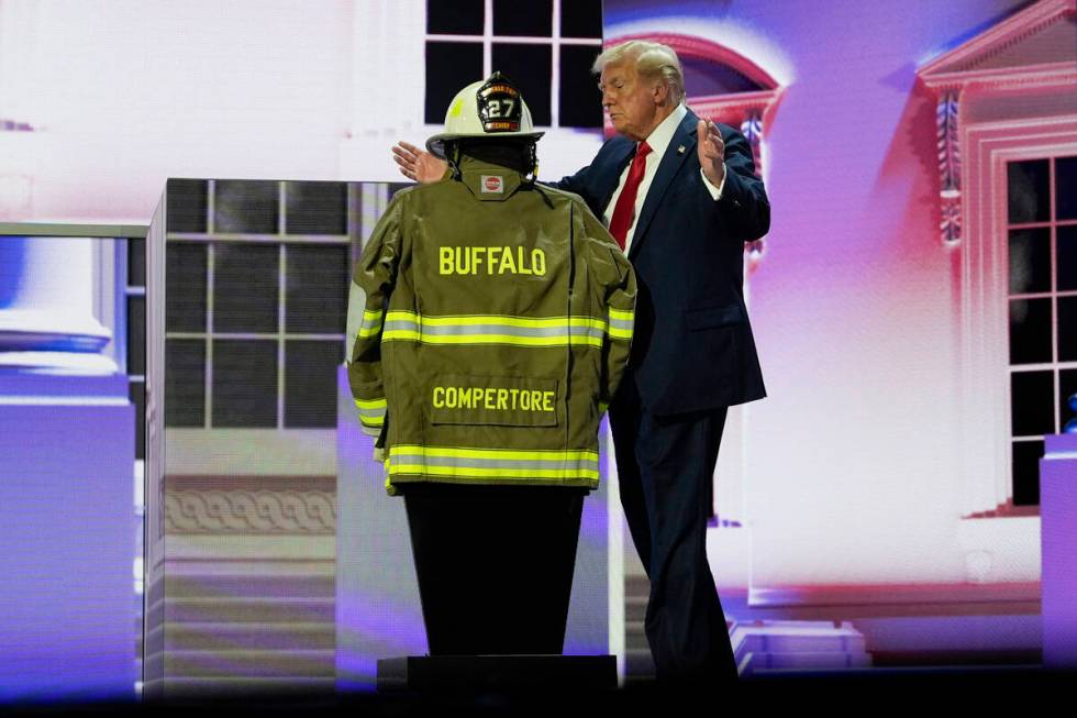 Republican presidential candidate former President Donald Trump stands next to the uniform of C ...