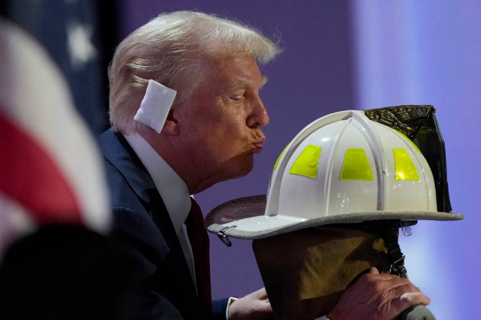 Republican presidential candidate former President Donald Trump kisses the helmet of Corey Comp ...