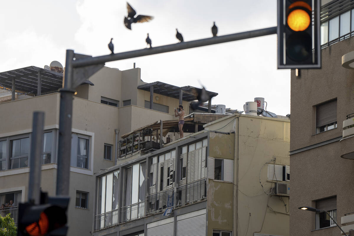 A man films the scene of an explosive drone attack in Tel Aviv, Israel, Friday, July 19, 2024. ...