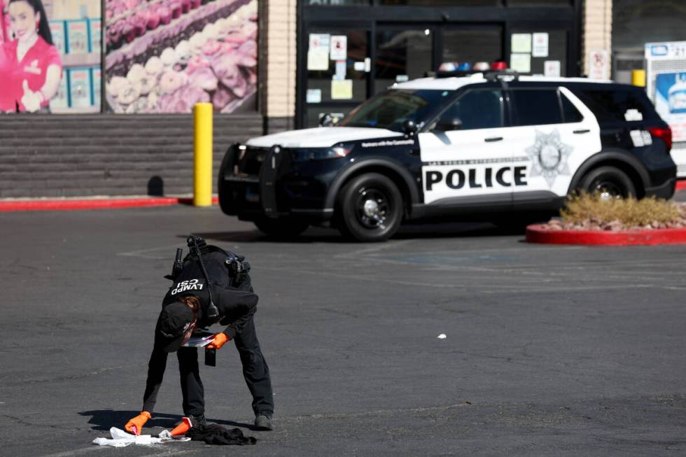 Metropolitan Police Department officers investigate a taped-off scene at a shopping center park ...